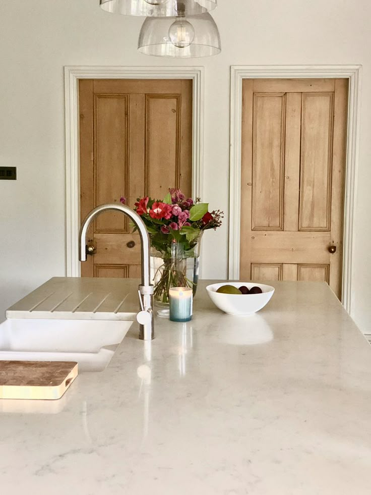 a kitchen counter with flowers in a vase on it and two bowls next to the sink