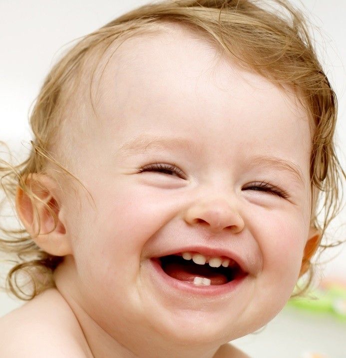 a baby laughing while sitting on the floor