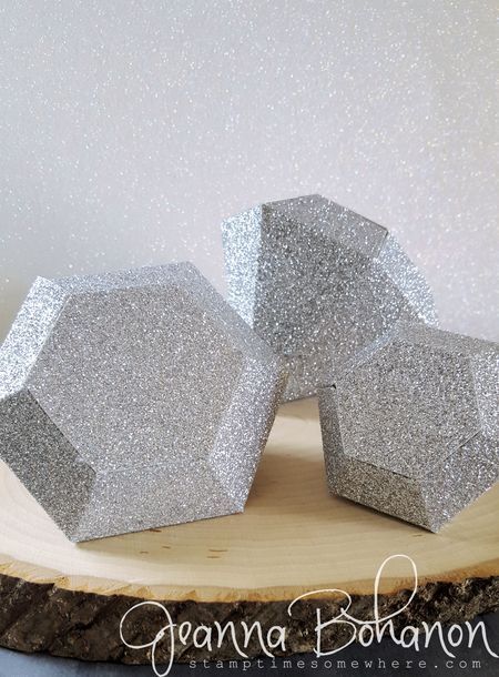 three silver glitter hexagonals sitting on top of a wooden board