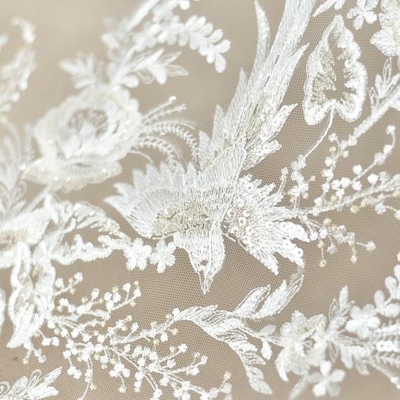 closeup of white lace on fabric with flowers and leaves in the center, as seen from above