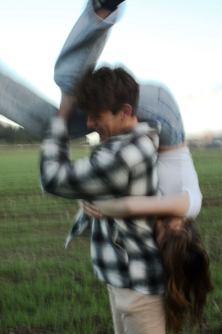 a man and woman hugging in the middle of a field