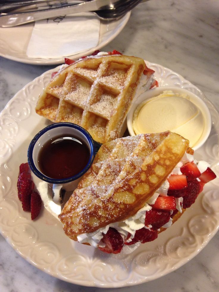 two waffles on a plate with syrup and strawberries next to each other