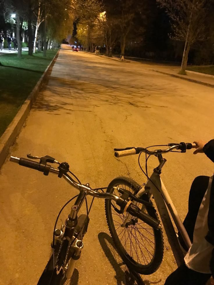 a bicycle parked on the side of a road at night with its handlebars still attached