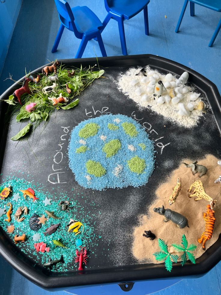 a child's chalkboard with animals and plants on it in front of blue chairs