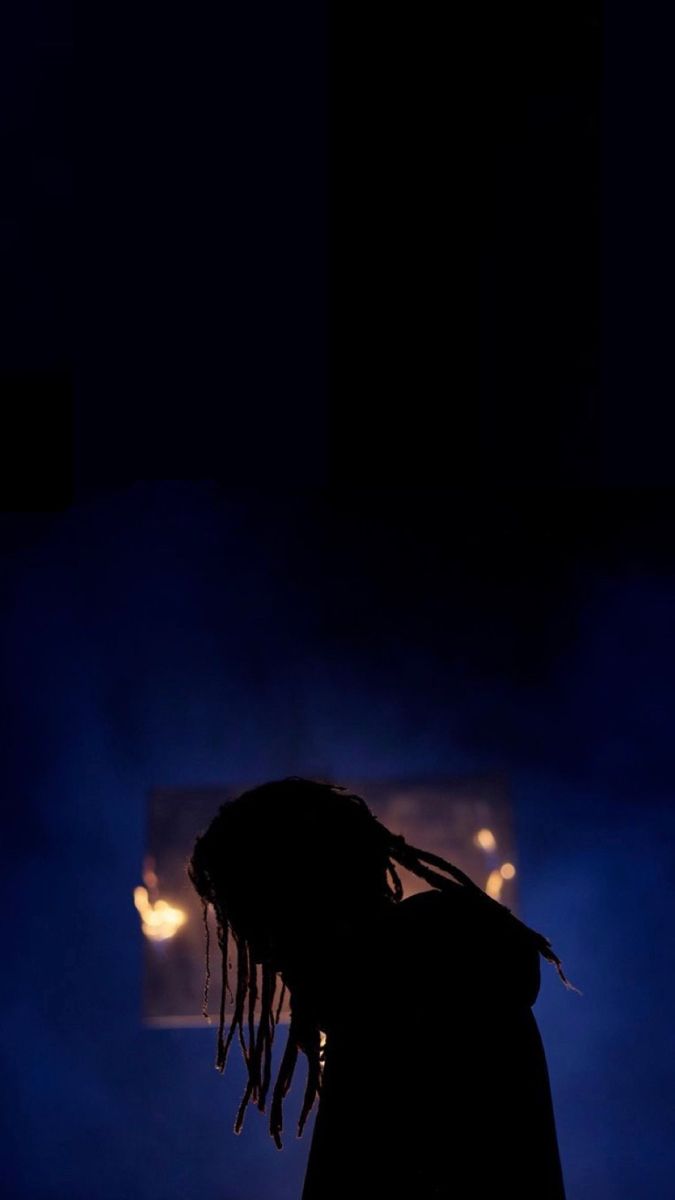 a person with dreadlocks standing in the dark