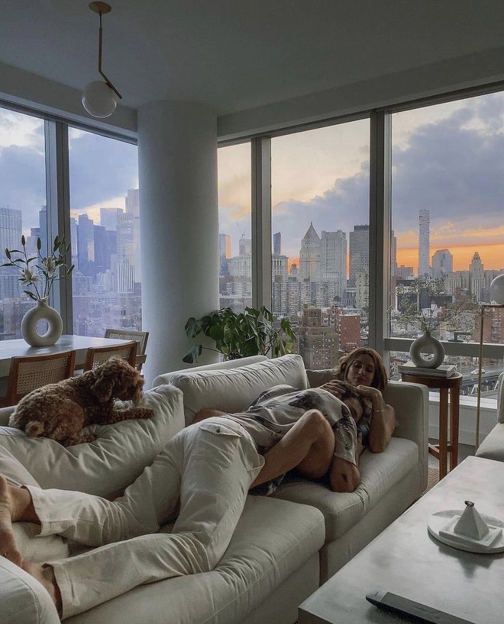 a man laying on top of a couch next to a window filled with lots of windows