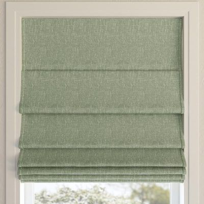 a green roman blind in front of a window with the blinds pulled back to reveal an open area