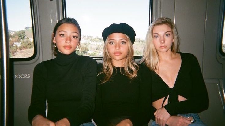 three women sitting next to each other on a train