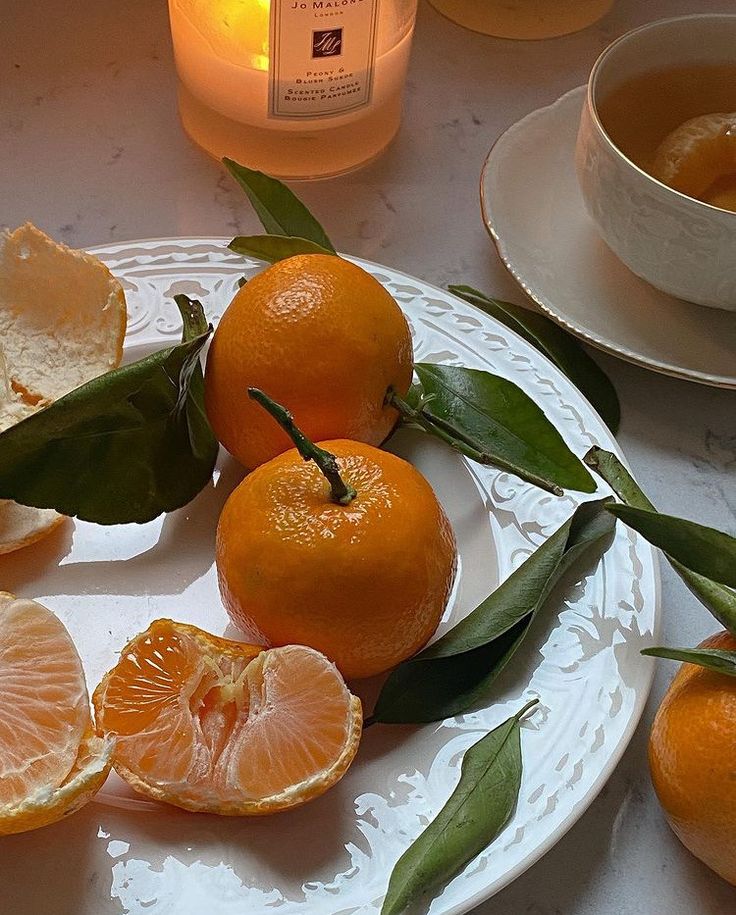 some oranges are sitting on a plate with leaves