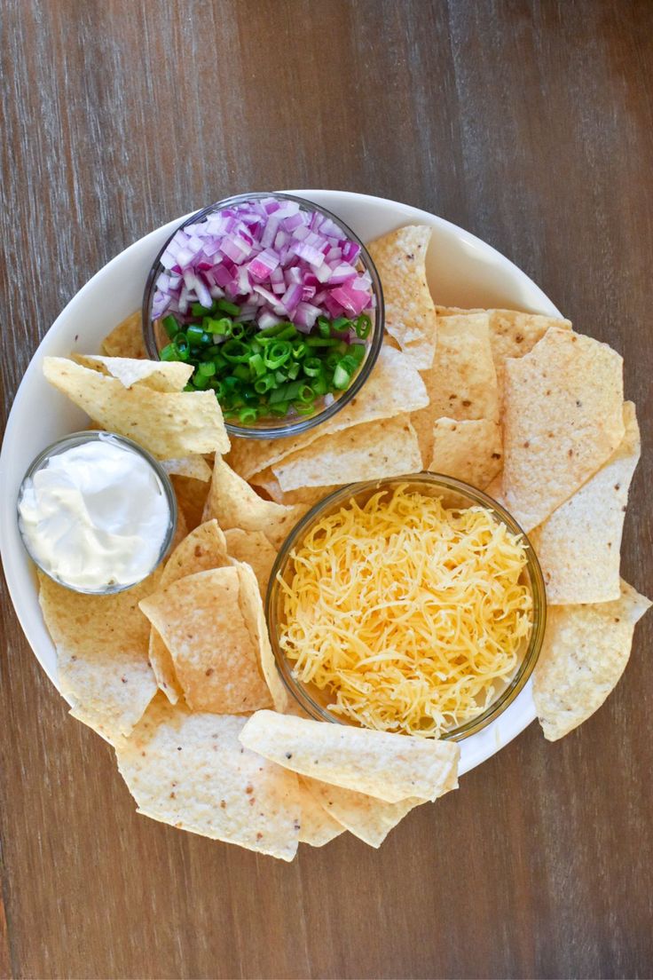 a white plate topped with chips and salsa next to tortilla chips on top of a wooden table