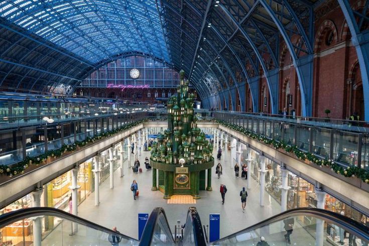 an escalator with a christmas tree in the middle and people walking around it