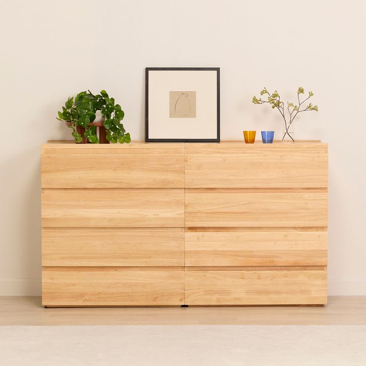 a wooden dresser sitting next to a potted plant