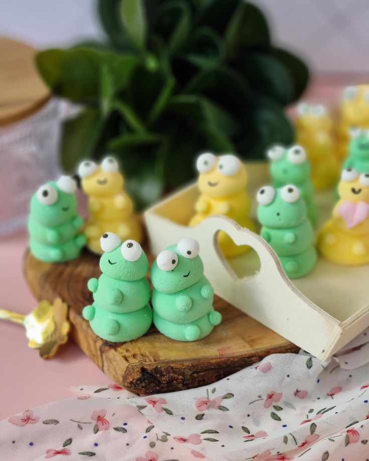 small green and yellow caterpillars sitting on a wooden board next to a potted plant