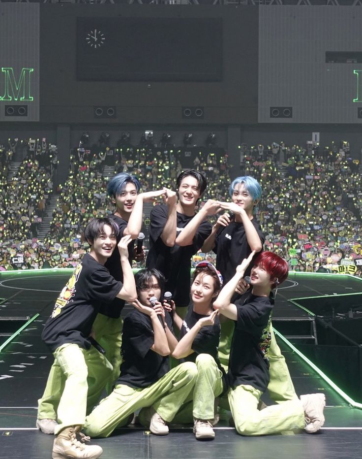 a group of young people standing on top of a stage with their arms in the air