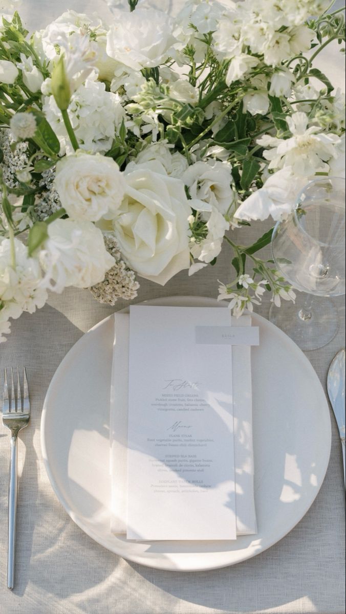 a table setting with white flowers and silverware