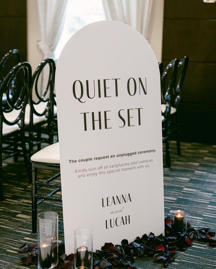 a sign that says quiet on the set sitting in front of some glasses and candles