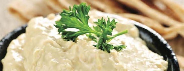 a black bowl filled with cream cheese and parsley