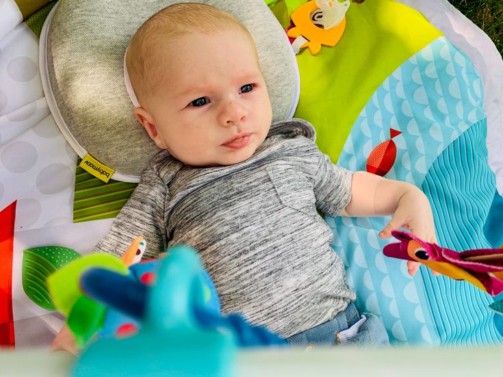 a baby laying in a play mat with toys