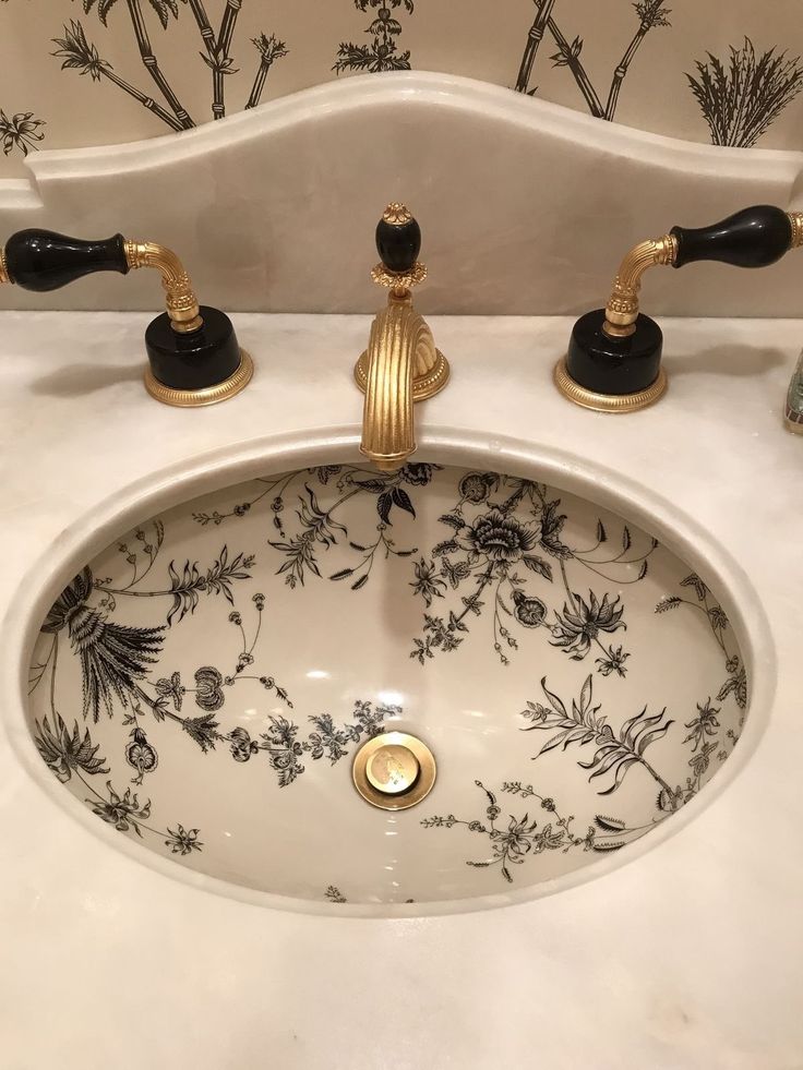 a white sink with black and gold faucets