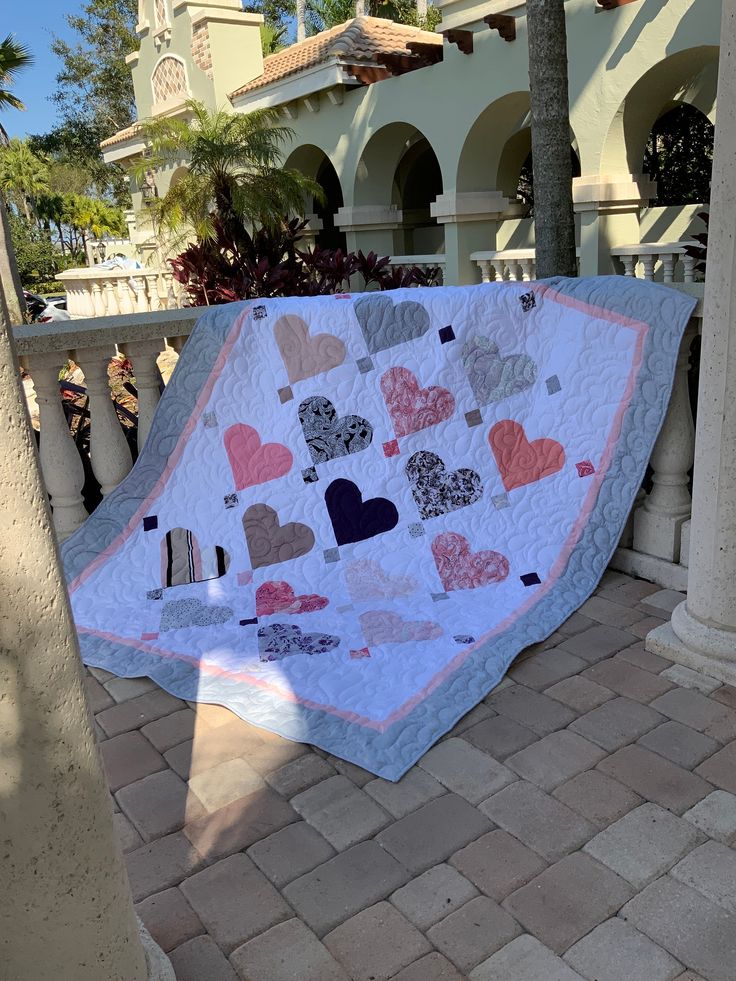 a quilted heart shaped blanket on the ground in front of a building