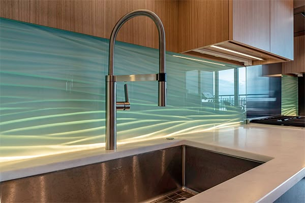 a kitchen sink under a faucet next to a counter top with lights on it