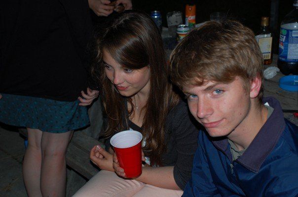 two young people sitting next to each other at a table with drinks in front of them