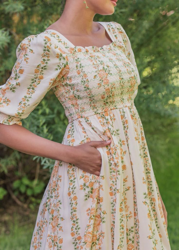 Lost In A Summer Romance The Rosaline Dress is a delightful blend of vintage charm and modern elegance. It features a lovely cream base adorned with delicate vertical floral stripes in soft yellow hues. The square neckline and puff sleeves add a romantic touch inspired by classic French Country design, while the flowing, full-length skirt enhances its graceful silhouette. Perfect for a garden party or a casual summer outing, this dress is designed to make you feel effortlessly chic and comfortab Feminine Dress With Straight Neckline And Gathered Sleeves, Beige Puff Sleeve Dress With Square Neck For Spring, Puff Sleeve Dress With Gathered Neckline For Garden Party, Beige Square Neck Puff Sleeve Dress For Spring, Square Neck Puff Sleeve Dress For Garden Party, Puff Sleeve Dress With Square Neck For Garden Party, Beige Square Neck Dress For Garden Party, Cream Puff Sleeve Dress With Square Neck For Spring, Cottagecore Square Neck Midi Dress For Garden Party