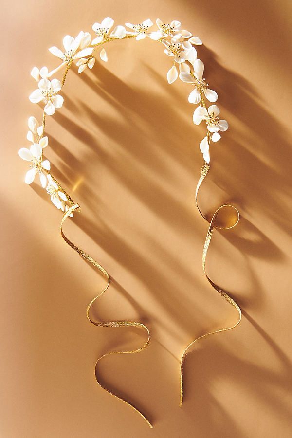 a gold headpiece with white flowers on it's side, against a tan background