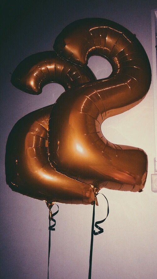 two gold balloons are in the shape of an eight on a wall next to a computer keyboard