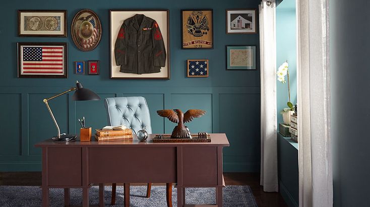 an office with blue walls and pictures on the wall above it, along with a chair