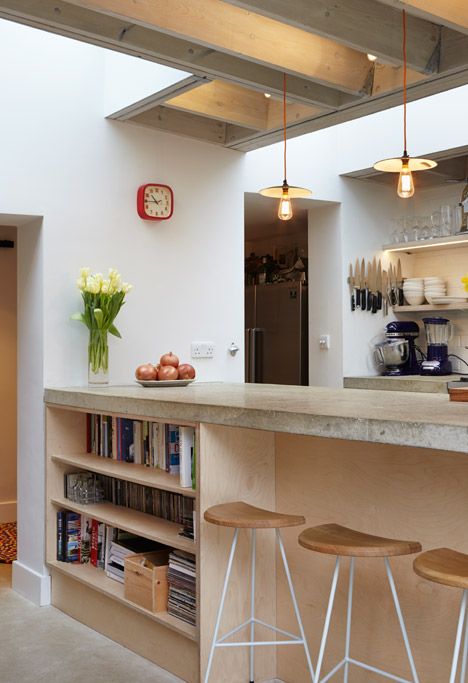 a kitchen with two bar stools next to a book shelf filled with cookbooks