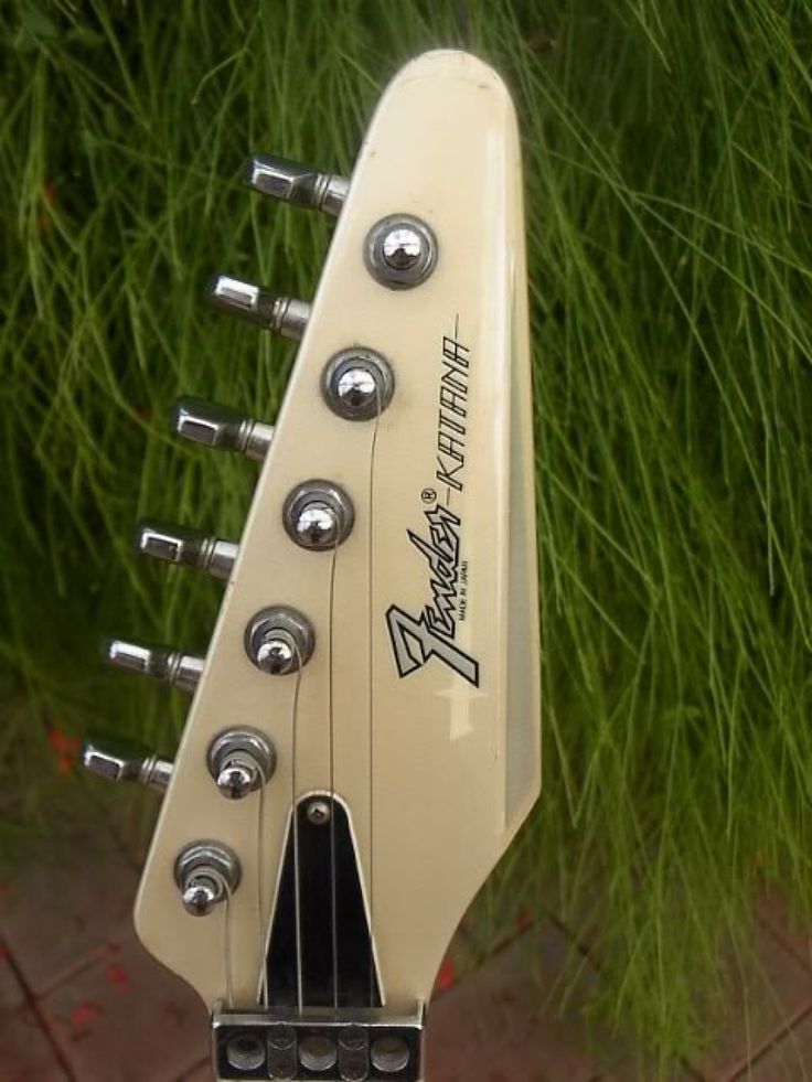 an electric guitar sitting in front of some grass