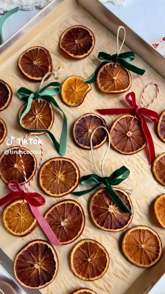 an assortment of dried oranges with ribbons and bows in a tray on a table