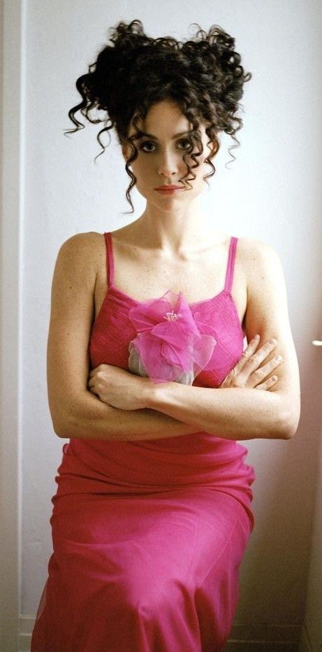 a woman in a pink dress with her arms crossed