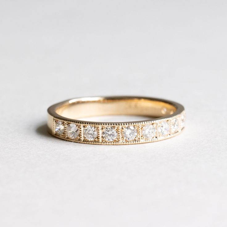 a yellow gold wedding band with five diamonds on the inside and outside, set against a plain white background