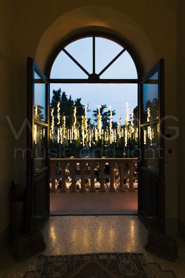 an open door leading to a balcony with lights on the trees in the back ground