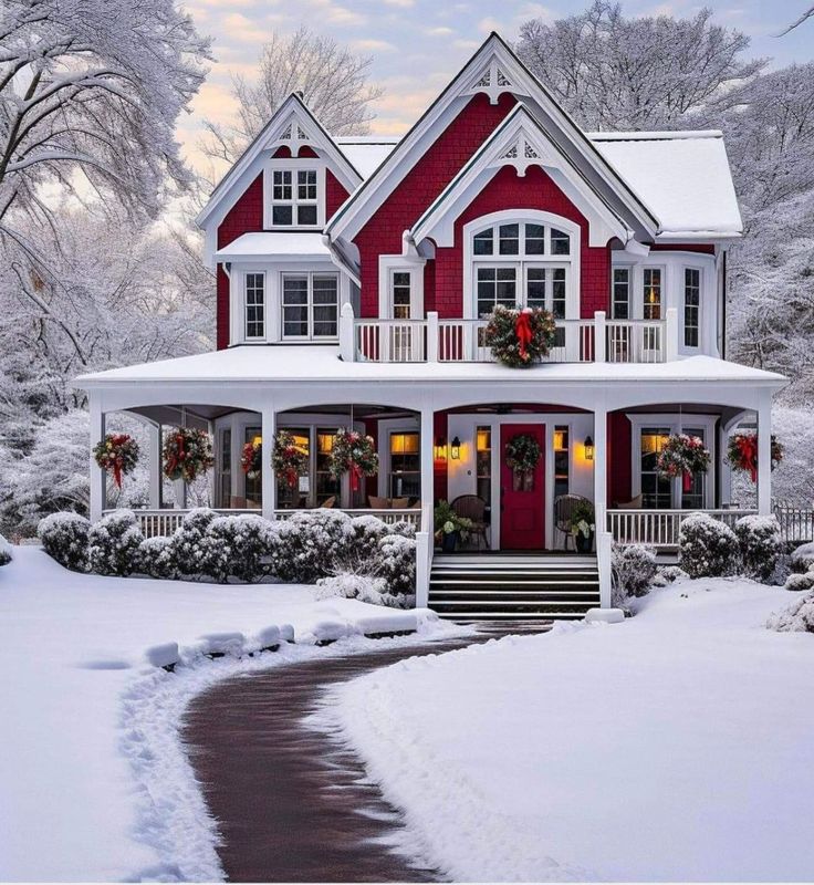 a red and white house with wreaths on the front porch in the wintertime