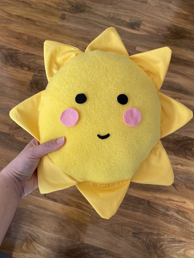 someone is holding up a yellow stuffed animal with pink eyes and an orange star on it's face