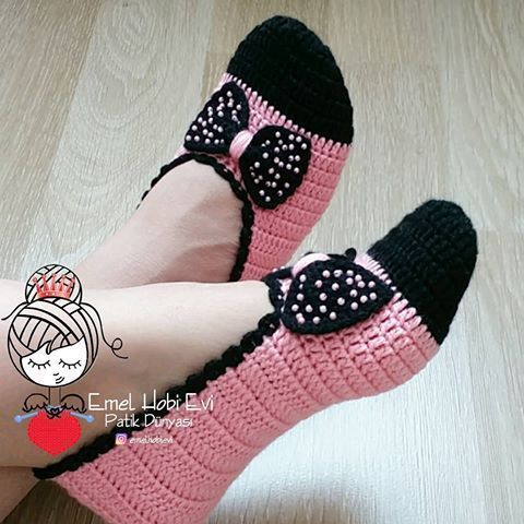 a woman's feet wearing pink and black crocheted slippers with bows