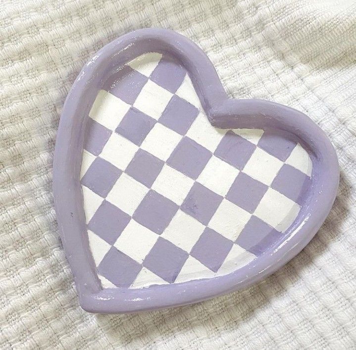 a purple heart shaped object sitting on top of a white cloth covered tablecloth with checkerboard pattern