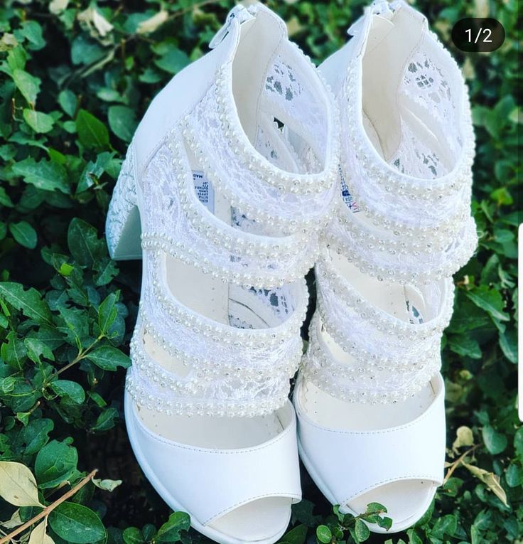 a pair of white shoes sitting on top of green bushes