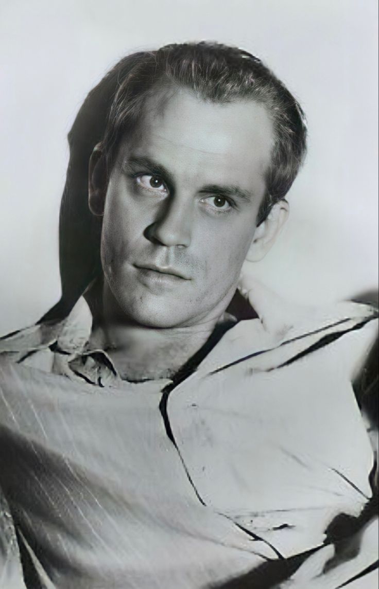 an old black and white photo of a man with his arm around the back of a chair