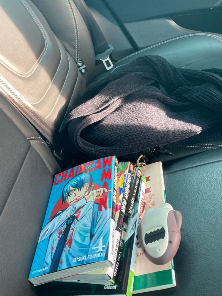 a bunch of books sitting on top of a car seat next to a book bag