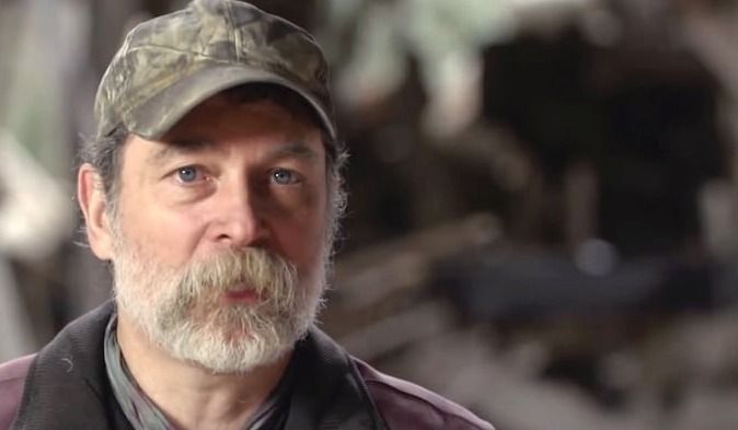 a man with a beard wearing a hat and vest