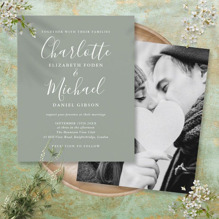 the wedding announcement card is displayed on top of a plate with flowers and greenery