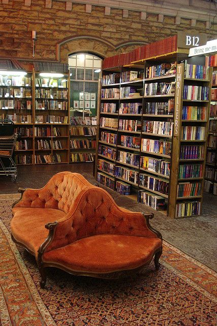 an orange couch sitting in front of a library filled with books