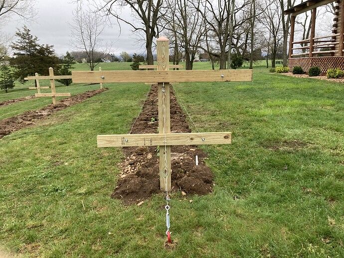 a wooden cross sitting on top of a lush green field