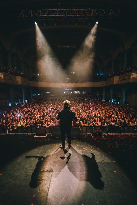 a man standing on top of a stage in front of a crowd at a concert