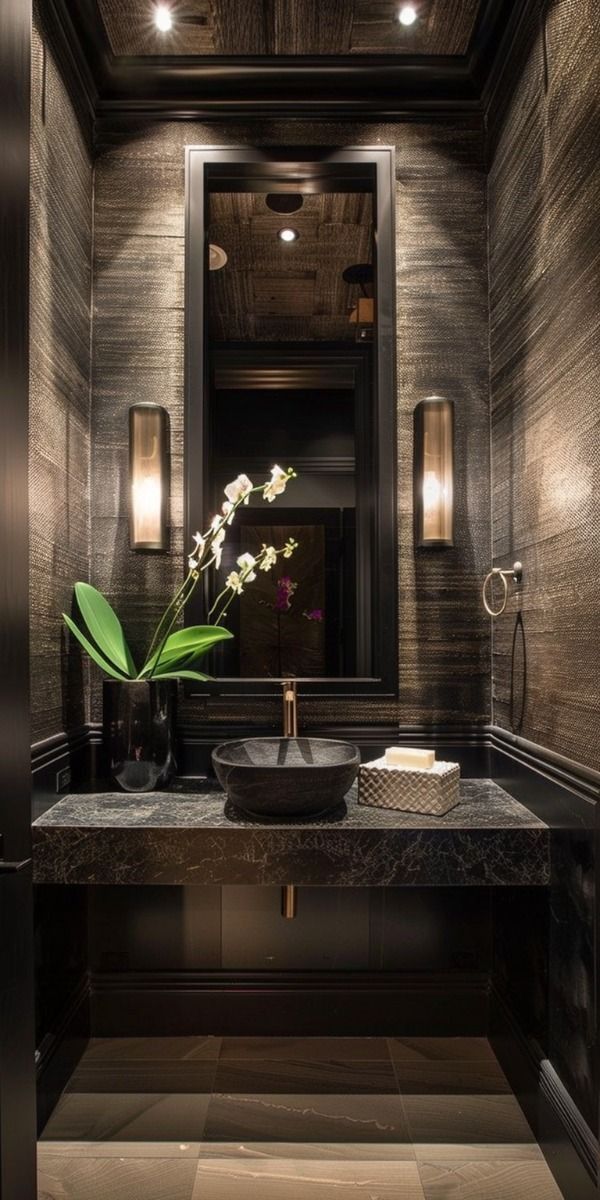 a bathroom sink sitting under a mirror next to a vase with flowers on top of it