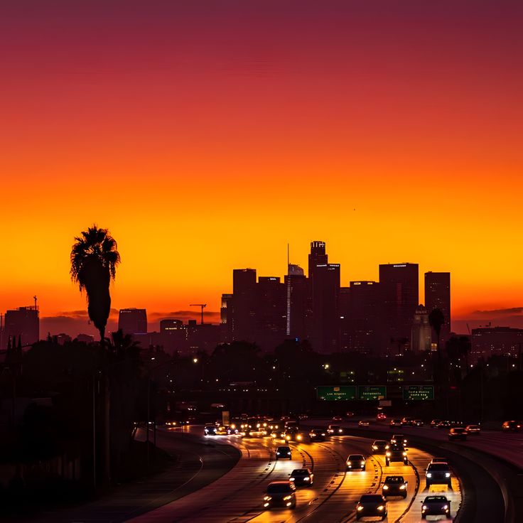 the city skyline is lit up at night with cars driving down the street in front of it